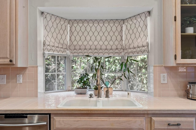 kitchen featuring dishwasher, tile counters, decorative backsplash, and a sink