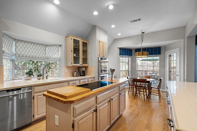 kitchen with light brown cabinets, a center island, light wood-type flooring, appliances with stainless steel finishes, and a sink