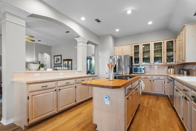 kitchen featuring light brown cabinets, a kitchen island, butcher block counters, stainless steel appliances, and ornate columns