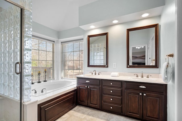 bathroom featuring tile patterned floors, a stall shower, a garden tub, and a sink