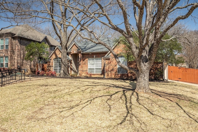 view of front of home featuring a front lawn, fence, and brick siding