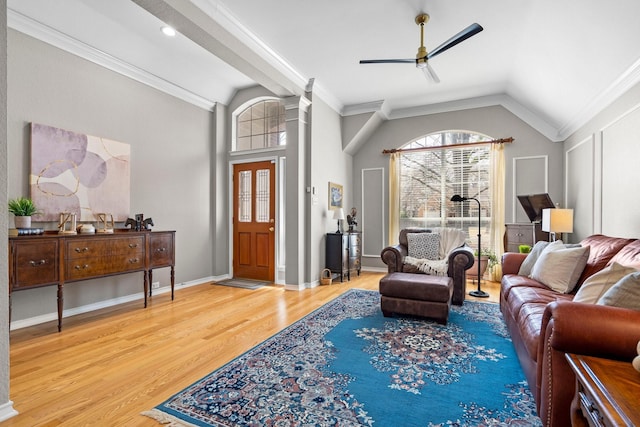 living area with wood finished floors, baseboards, lofted ceiling, decorative columns, and crown molding