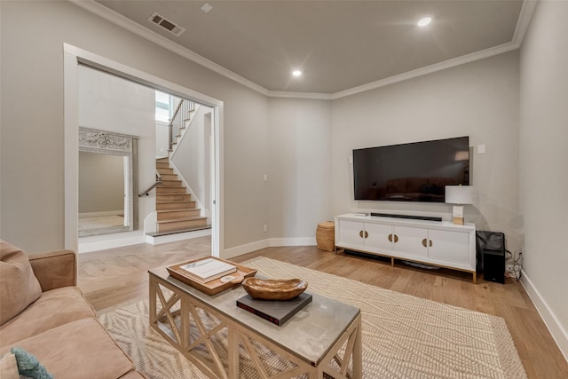 living room with light wood-style flooring, baseboards, visible vents, and ornamental molding