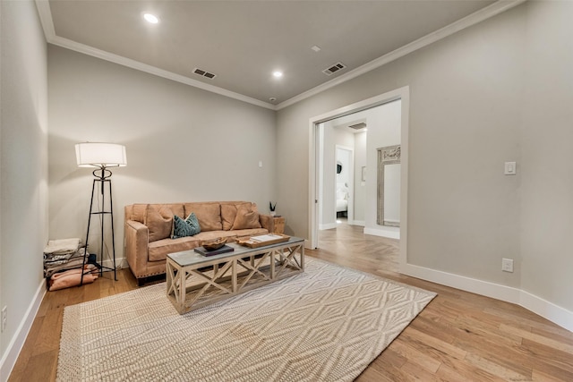 living room with crown molding, baseboards, visible vents, and light wood finished floors