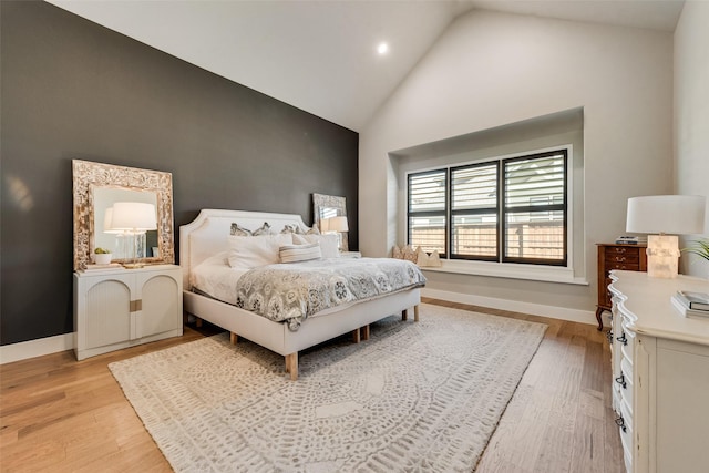 bedroom featuring light wood finished floors, high vaulted ceiling, and baseboards