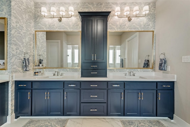 full bath featuring wallpapered walls, double vanity, marble finish floor, and a sink