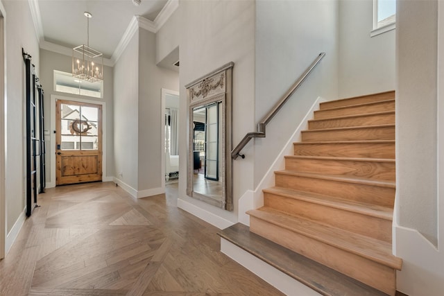 entryway featuring a healthy amount of sunlight, a towering ceiling, stairs, and crown molding