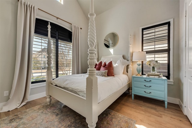 bedroom featuring baseboards, lofted ceiling, wood finished floors, and access to outside