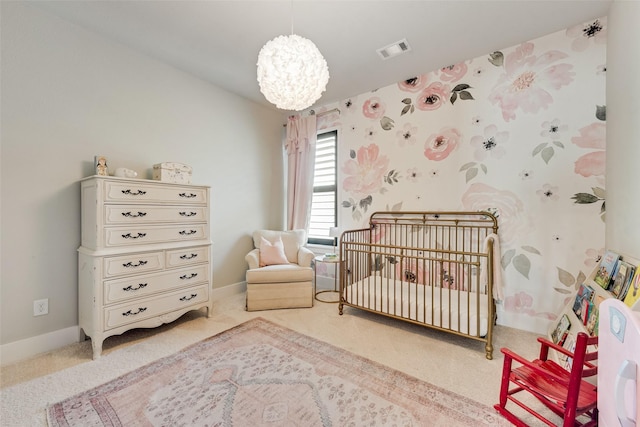 carpeted bedroom with visible vents, an inviting chandelier, a crib, and baseboards