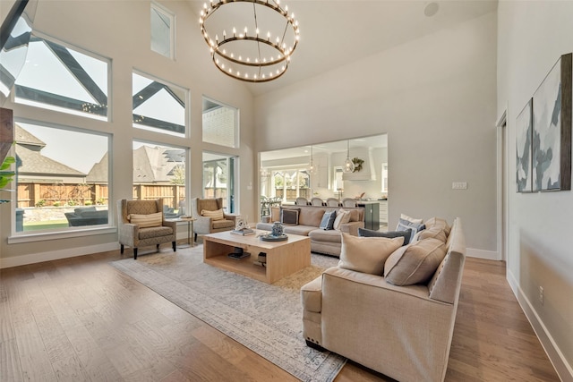 living area featuring a notable chandelier, plenty of natural light, wood finished floors, and baseboards