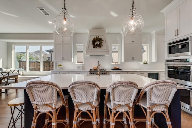 kitchen featuring beverage cooler, visible vents, light wood-style flooring, and light countertops