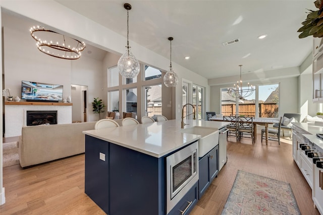 kitchen featuring visible vents, a sink, stainless steel appliances, blue cabinets, and open floor plan