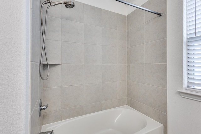 bathroom with bathing tub / shower combination and a textured wall