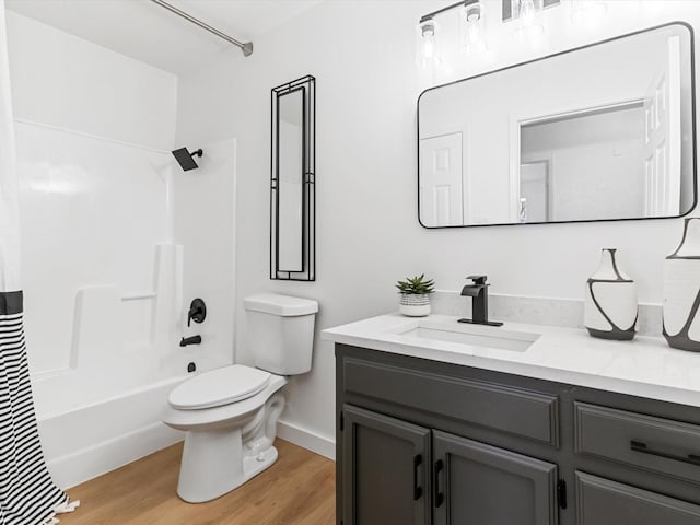 bathroom with toilet, wood finished floors, vanity, and shower / tub combination