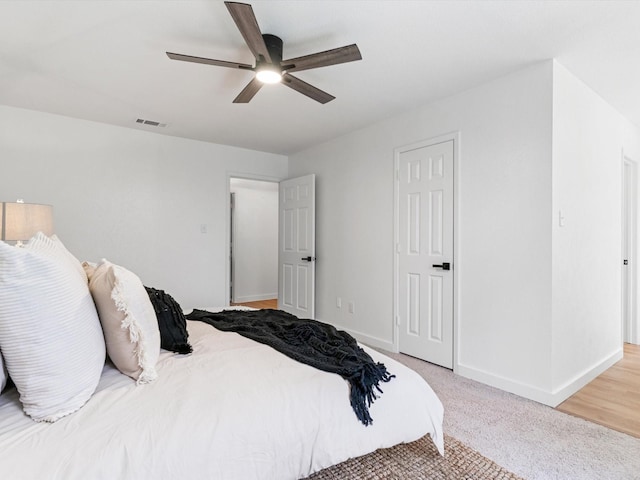 bedroom with visible vents, light colored carpet, a ceiling fan, and baseboards