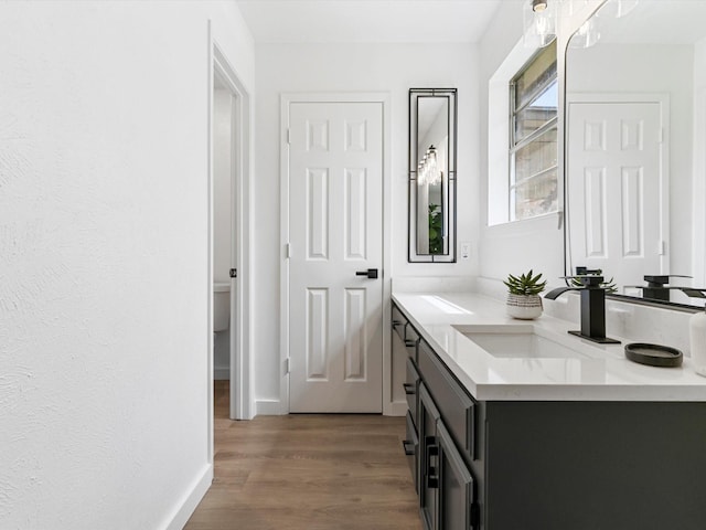 bathroom with vanity, wood finished floors, and baseboards