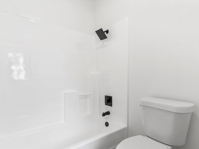 full bathroom with tub / shower combination, toilet, and a textured wall