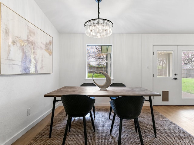 dining space featuring a notable chandelier, plenty of natural light, baseboards, and wood finished floors