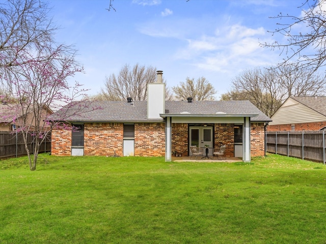 back of house with a patio area, a yard, a fenced backyard, and a chimney