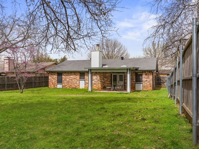 back of property with a yard, a patio, brick siding, and a fenced backyard