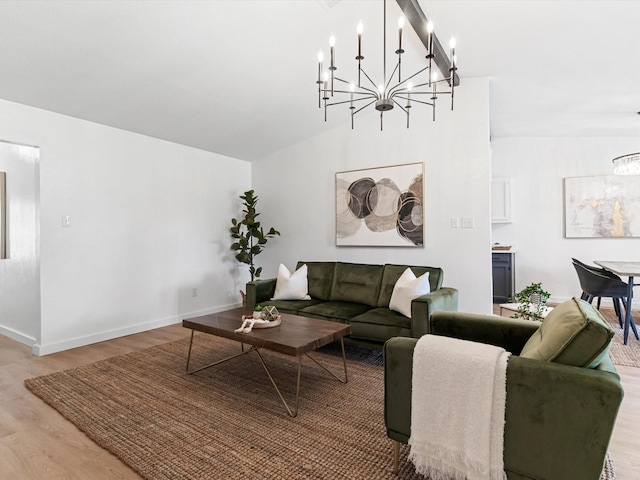 living area featuring a chandelier, light wood-style flooring, baseboards, and vaulted ceiling