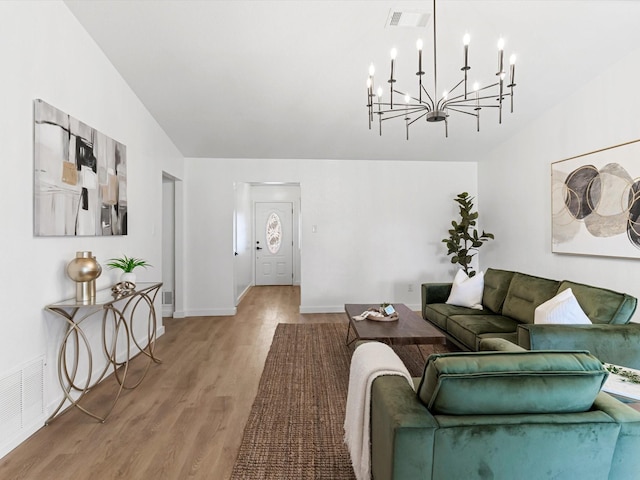 living room with visible vents, an inviting chandelier, light wood-style floors, and vaulted ceiling