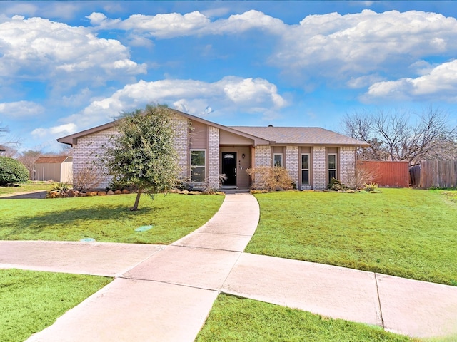 view of front of house with a front lawn, fence, and brick siding