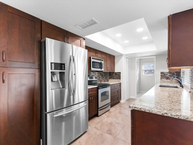 kitchen featuring visible vents, decorative backsplash, appliances with stainless steel finishes, a raised ceiling, and a sink