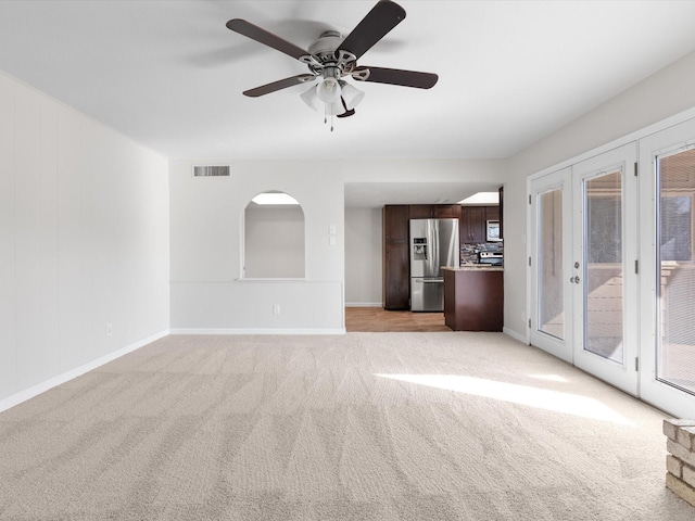 unfurnished living room with visible vents, light carpet, french doors, baseboards, and ceiling fan