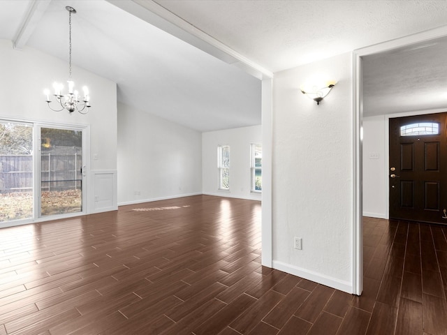 unfurnished living room featuring wood finish floors, baseboards, a chandelier, and vaulted ceiling with beams