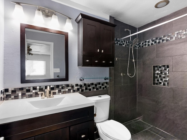 bathroom with vanity, tiled shower, decorative backsplash, tile walls, and toilet