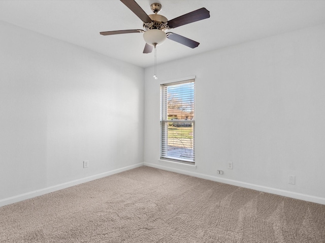 carpeted spare room featuring a ceiling fan and baseboards