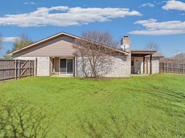 rear view of property with brick siding, a chimney, a fenced backyard, and a lawn