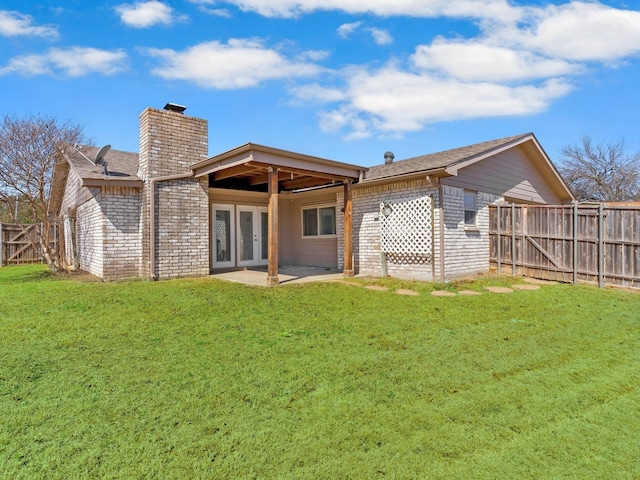 back of property featuring fence, a yard, brick siding, a chimney, and a patio area