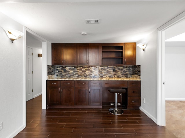 kitchen with open shelves, decorative backsplash, wood tiled floor, and built in desk