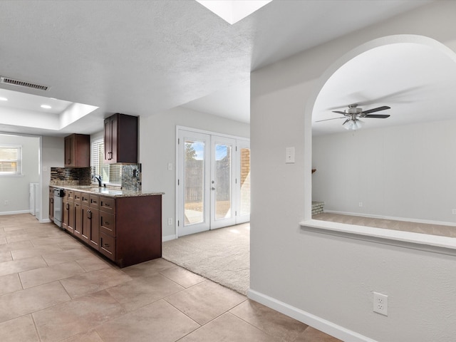 kitchen with visible vents, backsplash, dark brown cabinets, baseboards, and a sink