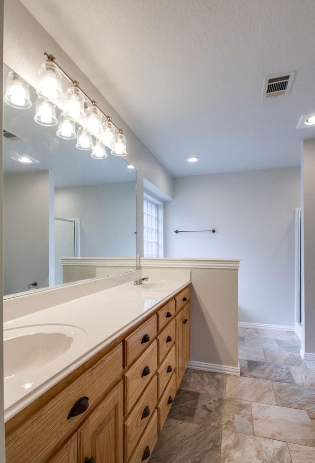 bathroom featuring double vanity, baseboards, visible vents, and a sink