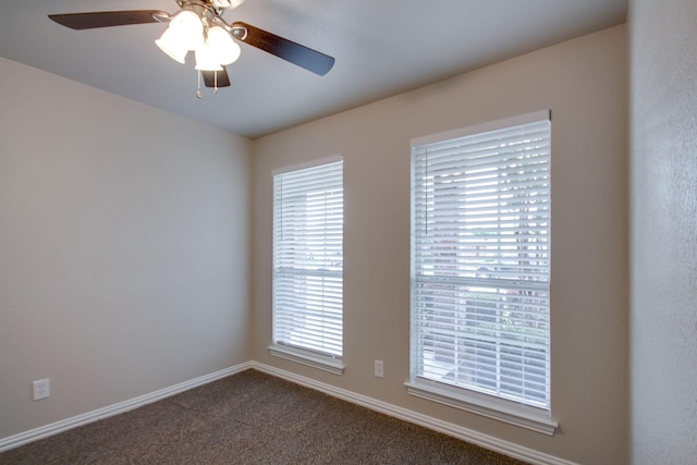 spare room with ceiling fan, baseboards, and dark colored carpet