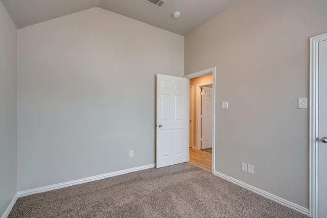 unfurnished bedroom featuring baseboards, lofted ceiling, and carpet