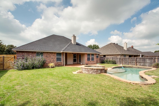 rear view of house with an in ground hot tub, a lawn, and a fenced backyard