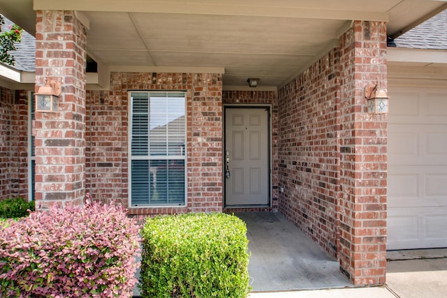 property entrance featuring brick siding and an attached garage