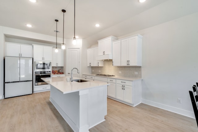 kitchen featuring appliances with stainless steel finishes, white cabinetry, light wood-style floors, and a sink