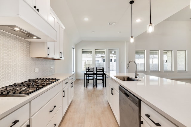 kitchen featuring light countertops, vaulted ceiling, custom exhaust hood, stainless steel appliances, and a sink