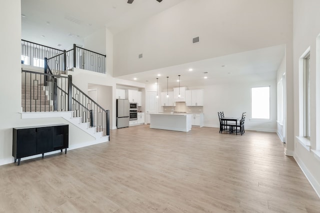 living room with a ceiling fan, baseboards, light wood finished floors, recessed lighting, and stairs