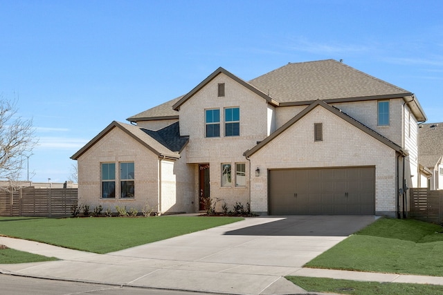 view of front of house with a front yard, fence, driveway, roof with shingles, and a garage