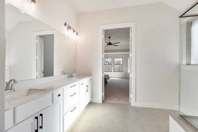 ensuite bathroom with lofted ceiling, tile patterned floors, and a sink