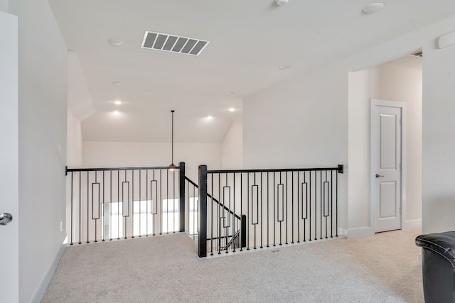 corridor with visible vents, an upstairs landing, carpet floors, baseboards, and vaulted ceiling