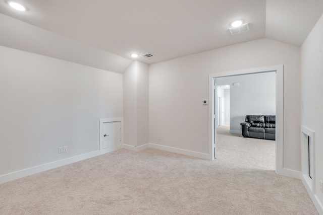 spare room with visible vents, carpet flooring, and vaulted ceiling