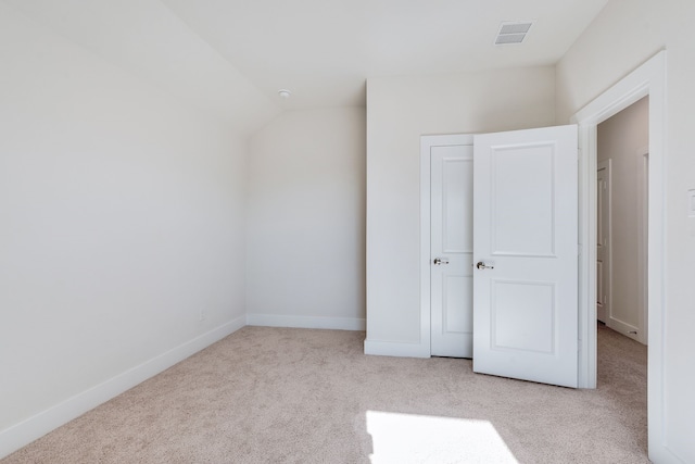 unfurnished bedroom with visible vents, lofted ceiling, baseboards, and carpet floors