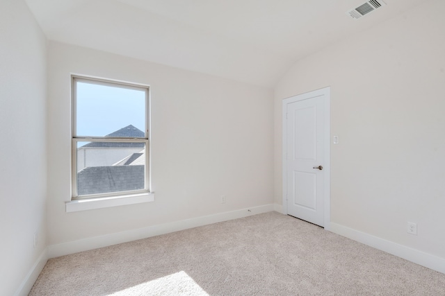 carpeted spare room with vaulted ceiling, baseboards, and visible vents